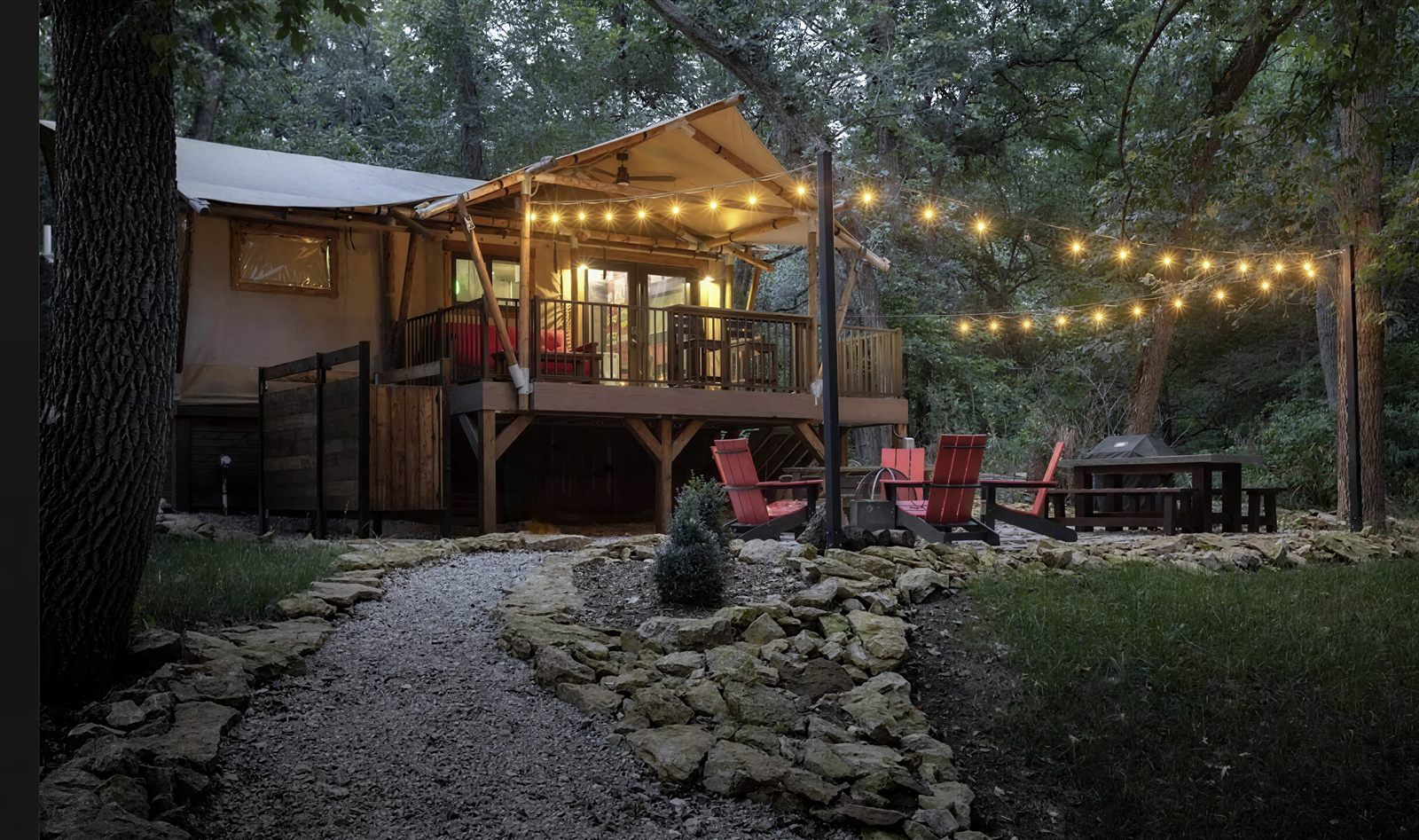 Safari cabin glowing under string lights at dusk