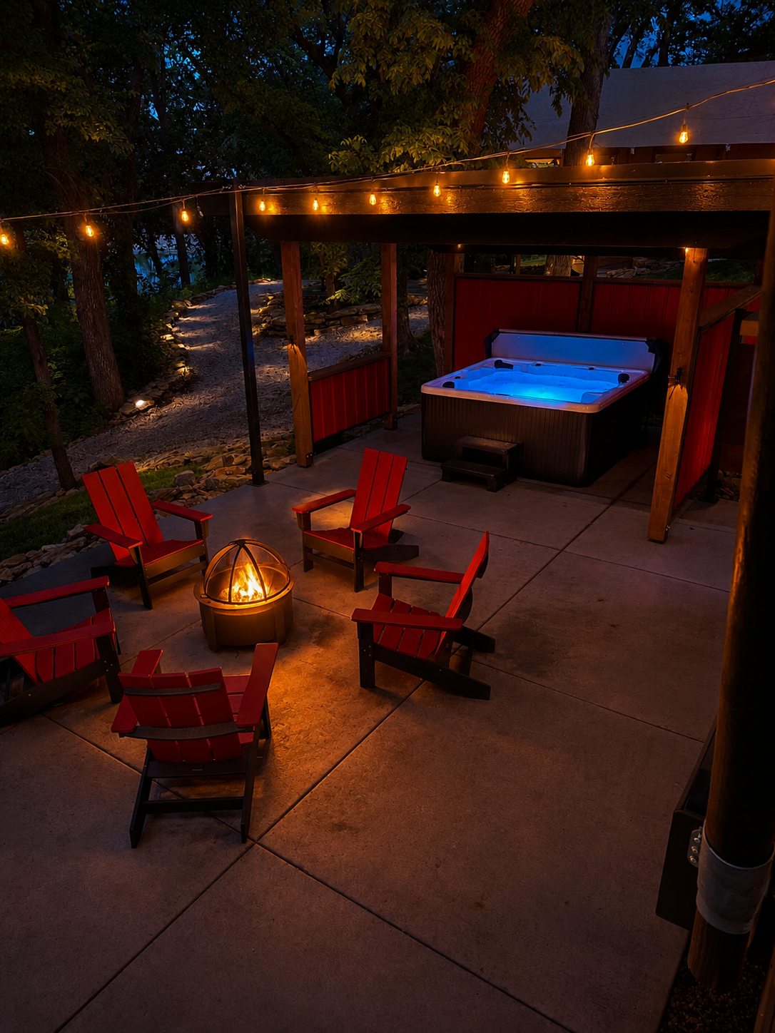 Hot tub glowing under the pergola at dusk, fire pit and string lights beside it