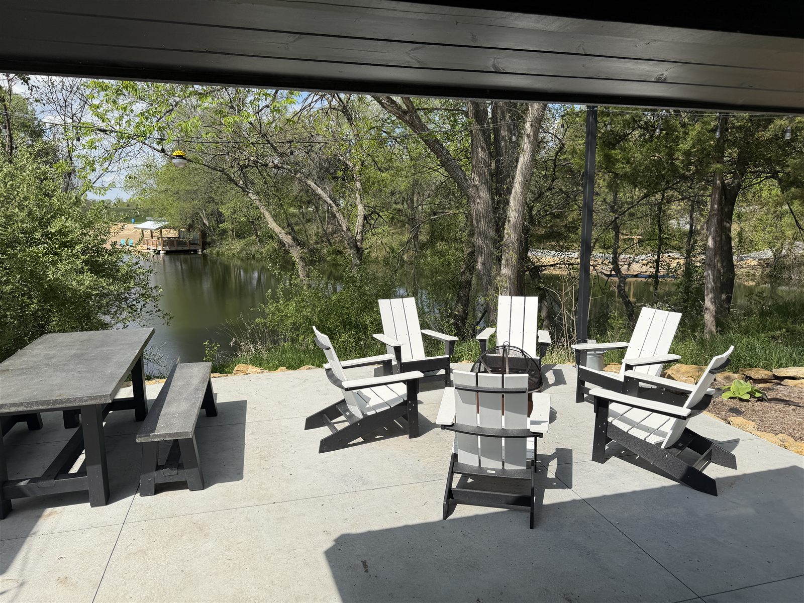 Lakeside patio with chairs around a fire pit and a picnic table over the water